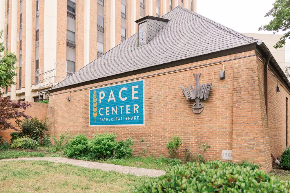 The facade of The Pace Center's brick building boasting a large blue Pace Center logo in the center.